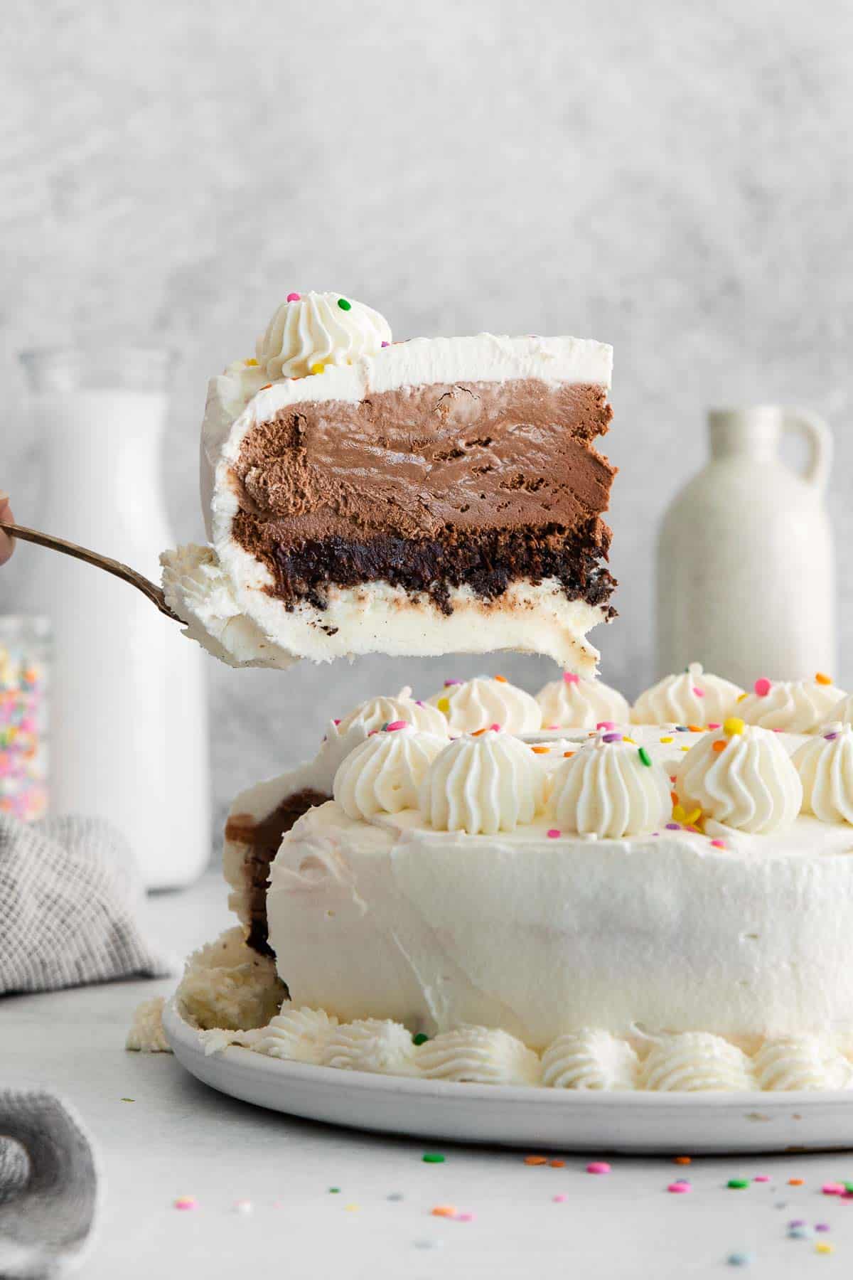 Gluten-free ice cream cake on a counter top, with a slice being taken out of the cake