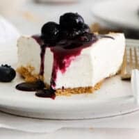 A slice of gluten-free no-bake cheesecake on a plate with blueberries on top