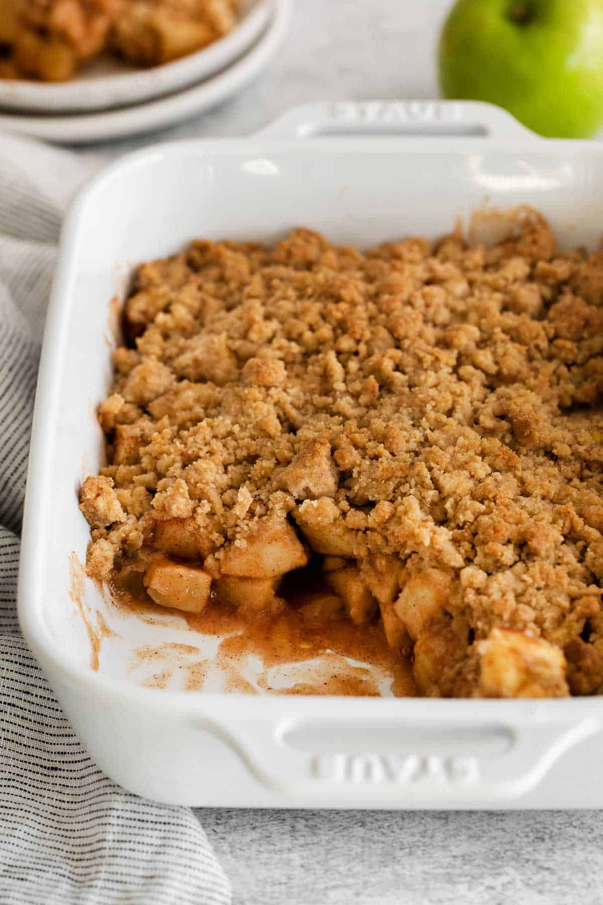 A dish of apple crumble, with a serving scooped out