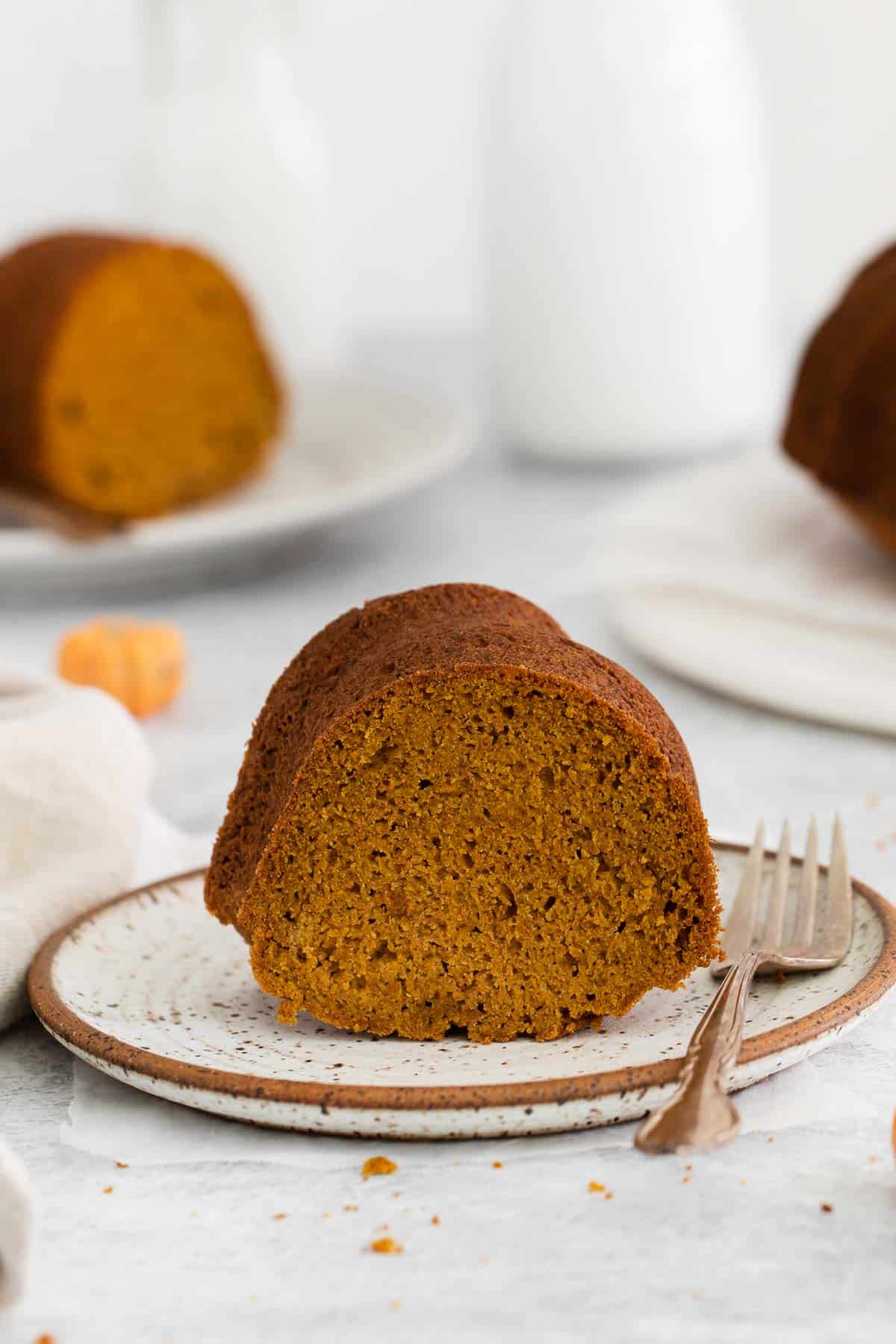 A slice of gluten-free pumpkin cake on a plate with a fork next to it