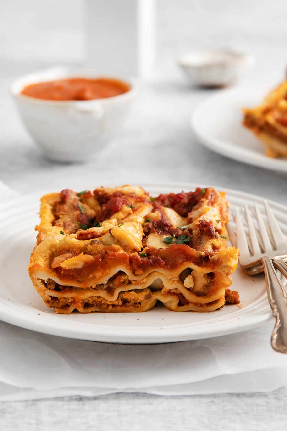 A slice of dairy-free lasagna on a plate with a fork