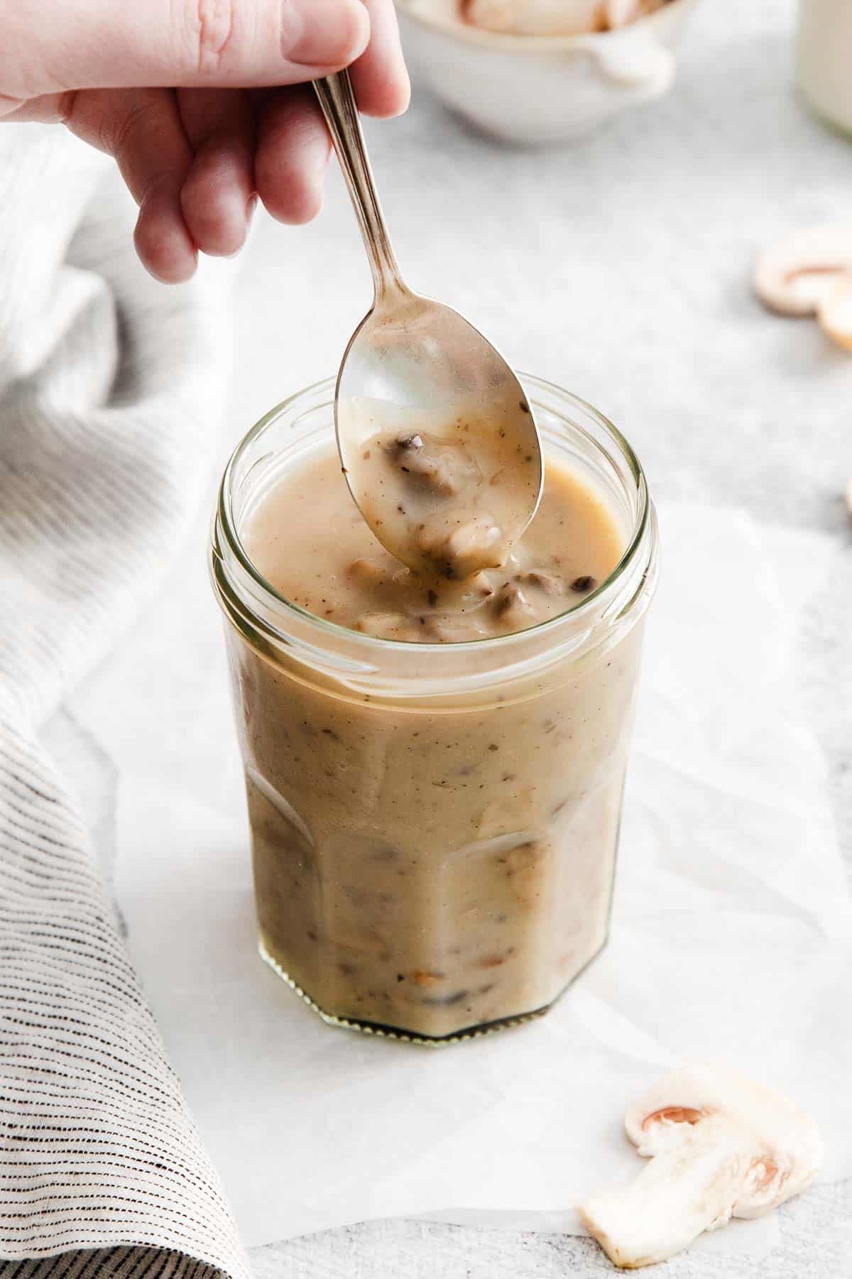 A spoon dipping into a cup of cream of mushroom soup