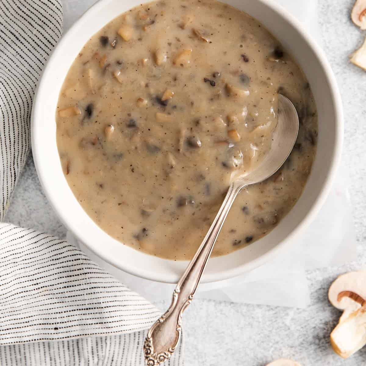 A bowl of cream of mushroom soup with a spoon in it