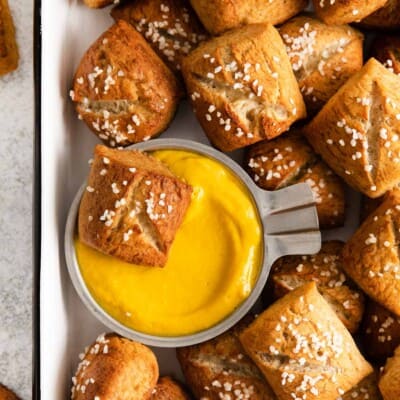 a close-up photo of gluten-free soft pretzel bites with cheese dip