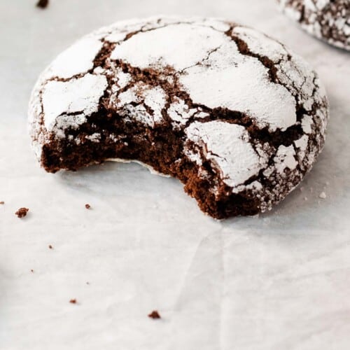 one gluten-free chocolate crinkle cookie with a bite taken out of it