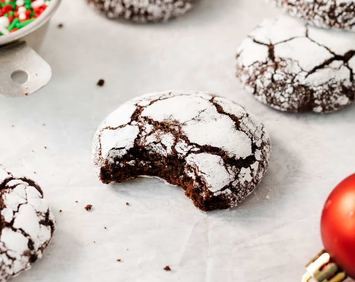 A gluten-free chocolate crinkle cookie with a bite taken out of it