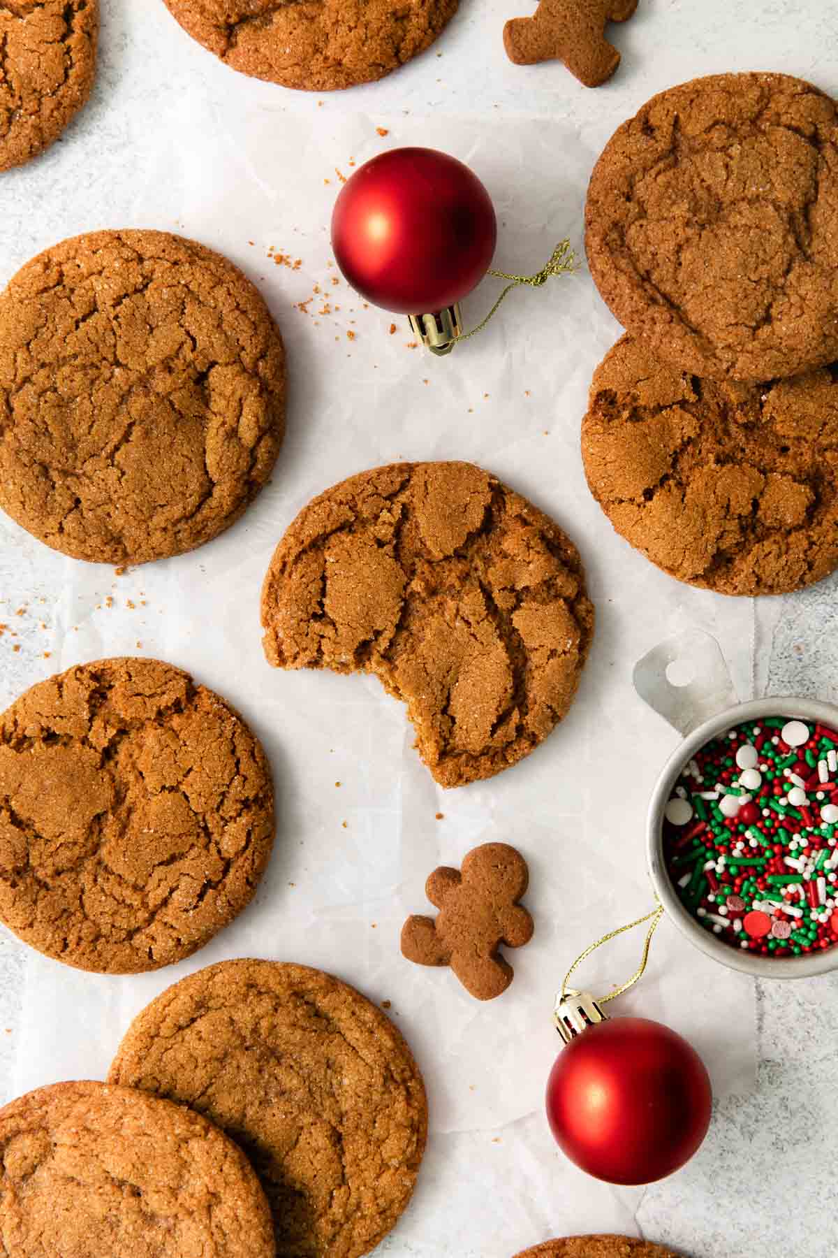 Gingersnaps and ornaments laid on a counter top, with a bite taken out of one cookie