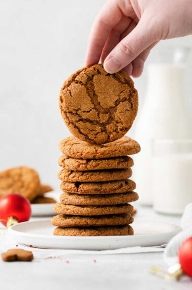 A stack of gingersnaps with a hand picking up the cookie on top
