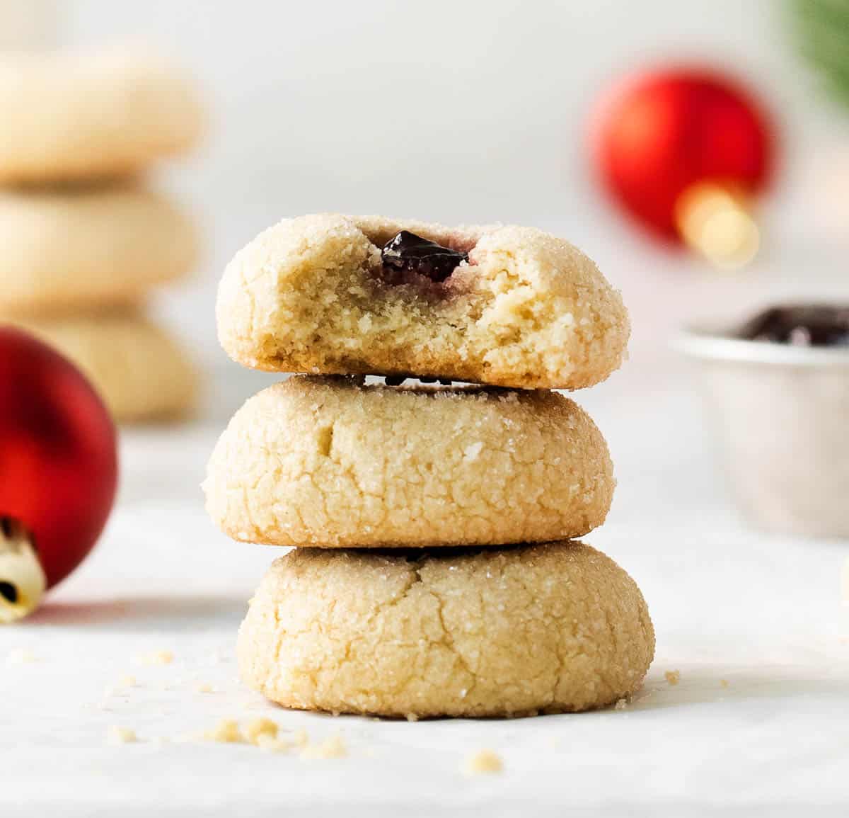 Gluten-free thumbprint cookies stacked on top of each other, with a bite taken out of the one on top