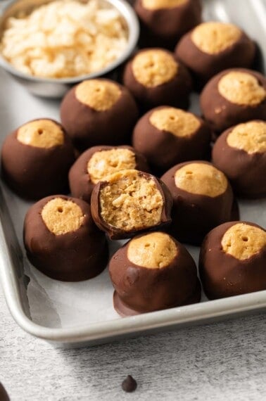 A close-up photo of peanut butter balls with Rice Krispies on a baking sheet