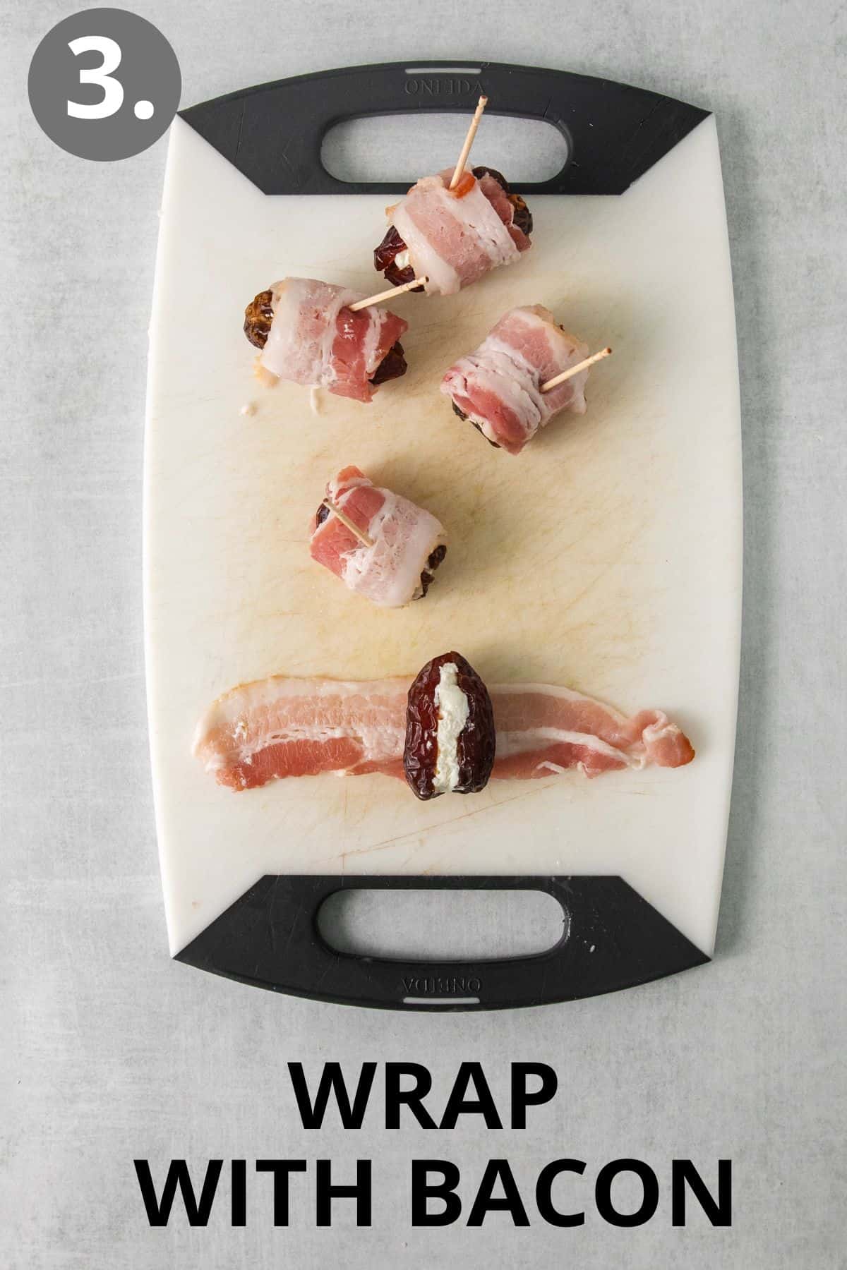 Cheese-filled dates being wrapped with raw bacon on a cutting board