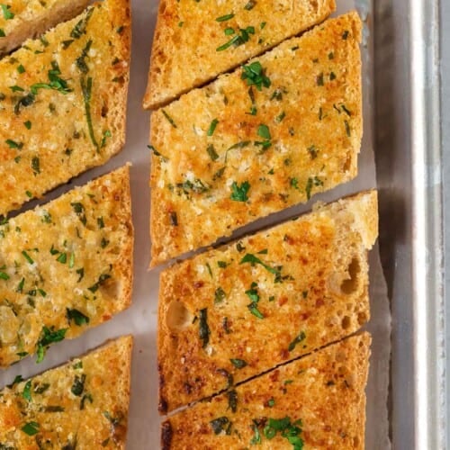 An overhead view of gluten-free garlic bread sliced on a baking sheet