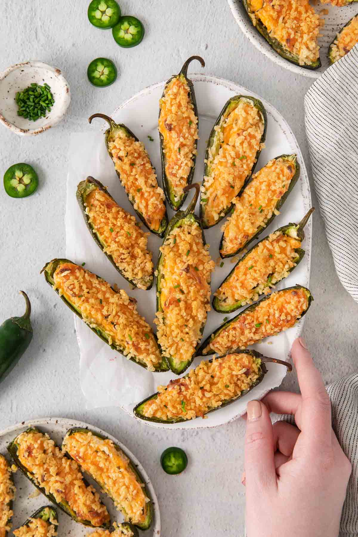 Gluten-free jalapeno poppers on a tray with a hand touching the tray