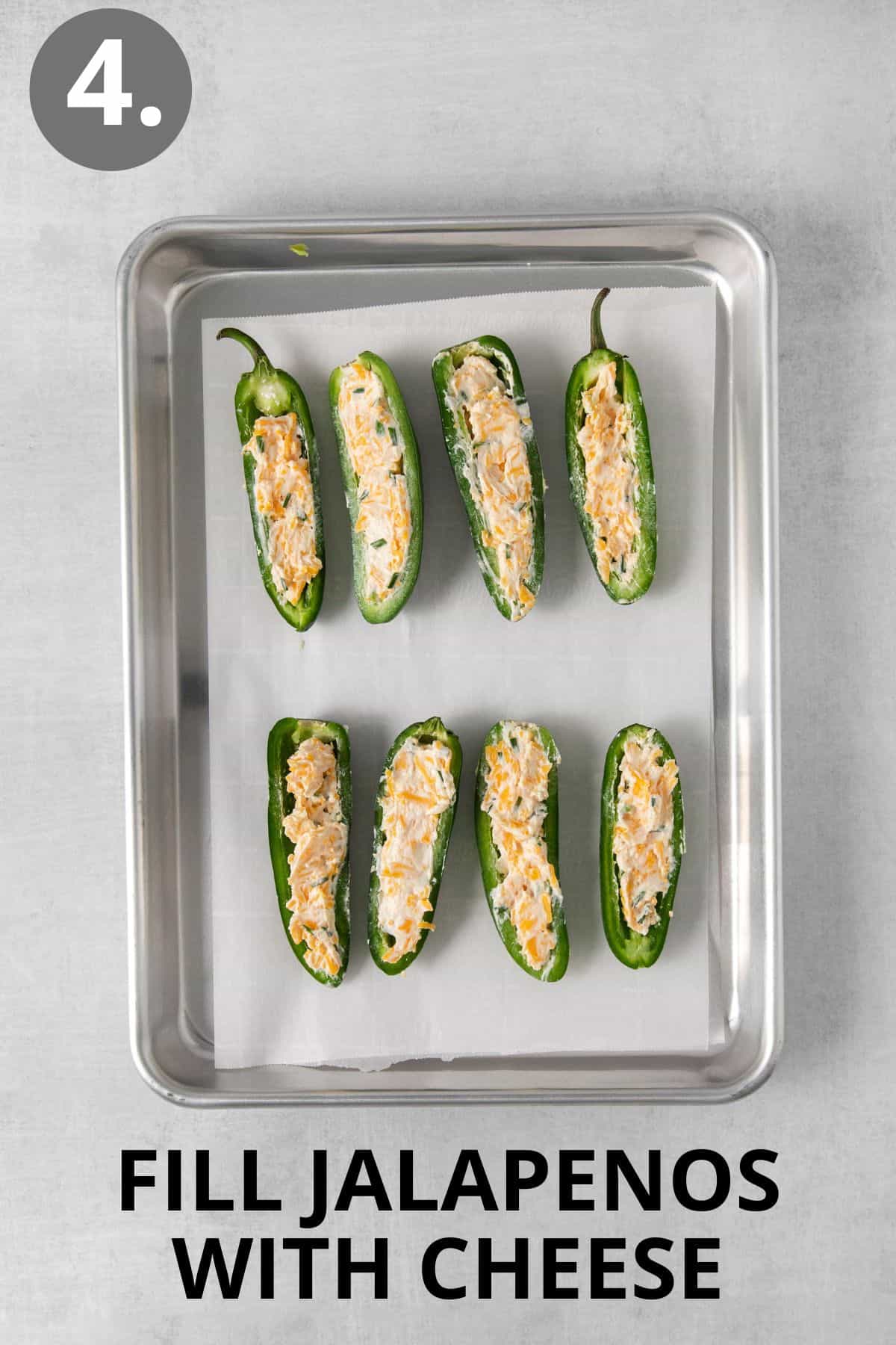 Jalapenos filled with cheese on a baking sheet