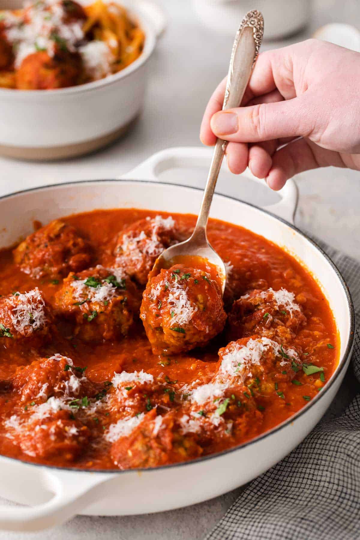 Gluten-free meatballs in a serving dish and a fork reaching in to pick up a meatball