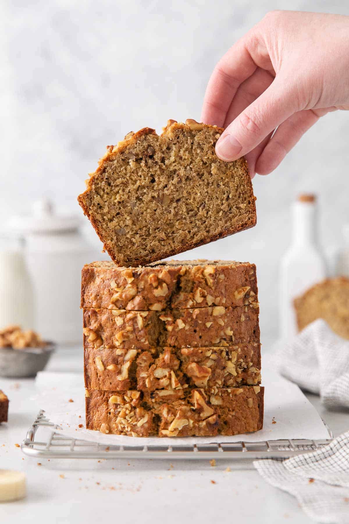 A hand picking up a slice of oat flour banana bread