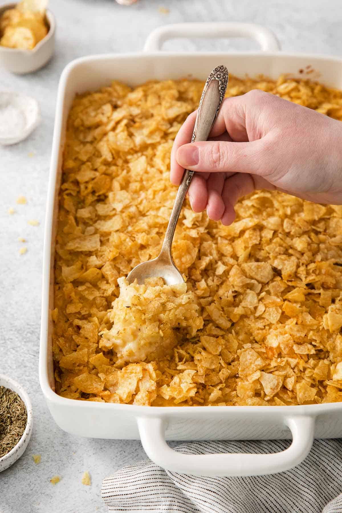 gluten-free cheesy potatoes in a baking dish with a serving spoon in it