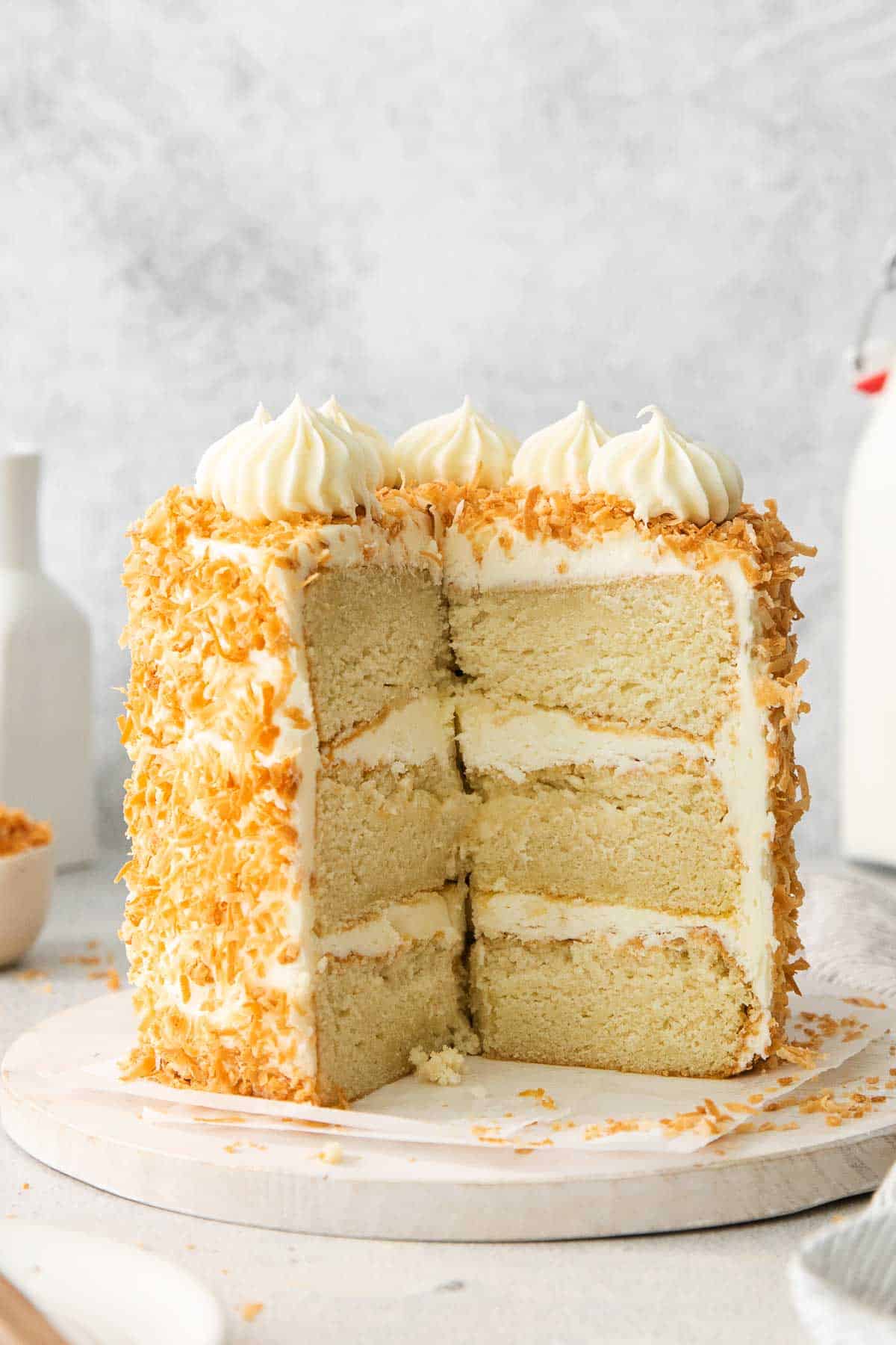 Coconut layer cake on a platter with a section sliced out of it