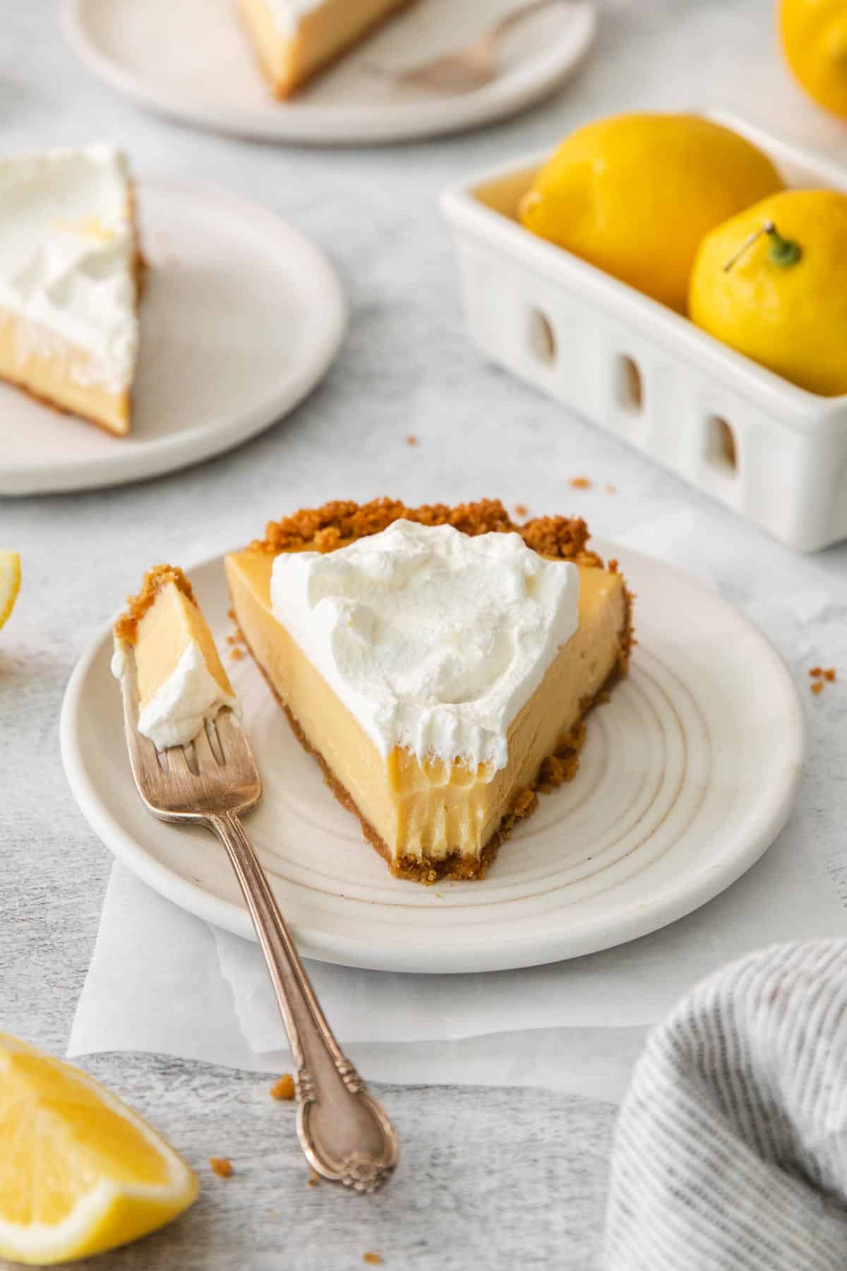 A slice of lemon cream pie on a plate with a fork