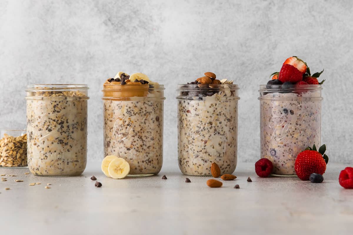 Four types of gluten-free overnight oats in Mason jars on a counter top