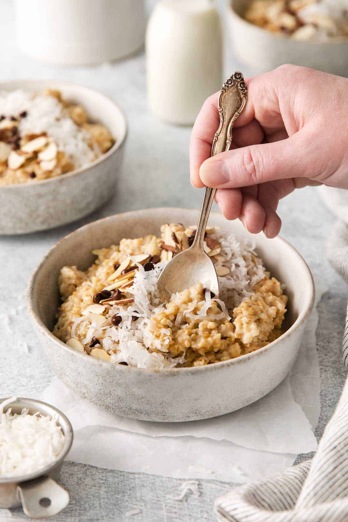 A bowl of steel cut oats, and a hand scooping up a bite with a spoon