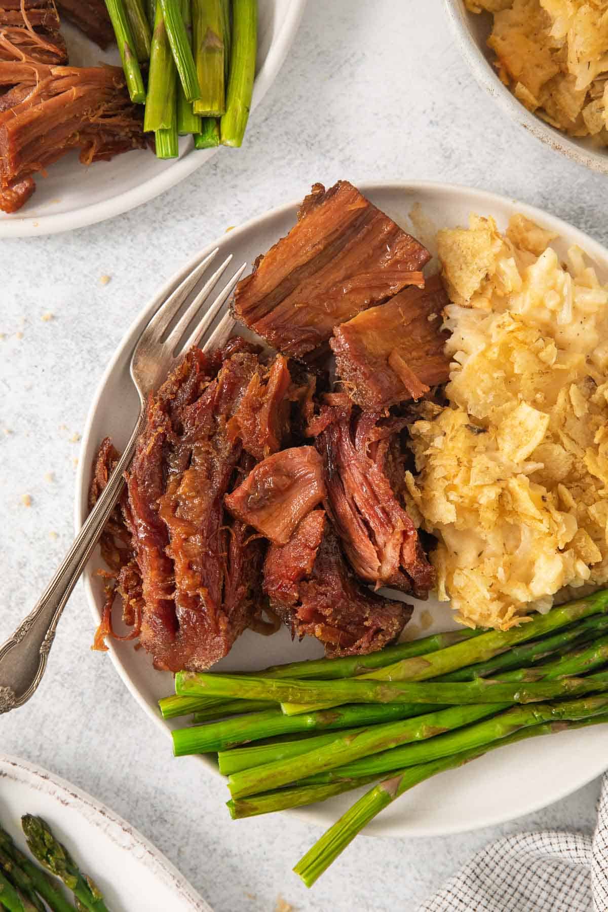gluten-free ham on a plate with cheesy potatoes and asparagus
