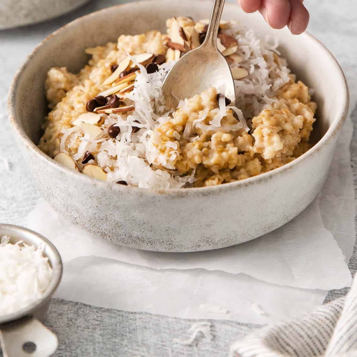 A bowl of steel cut oats with toppings and a spoon dipping into the oats