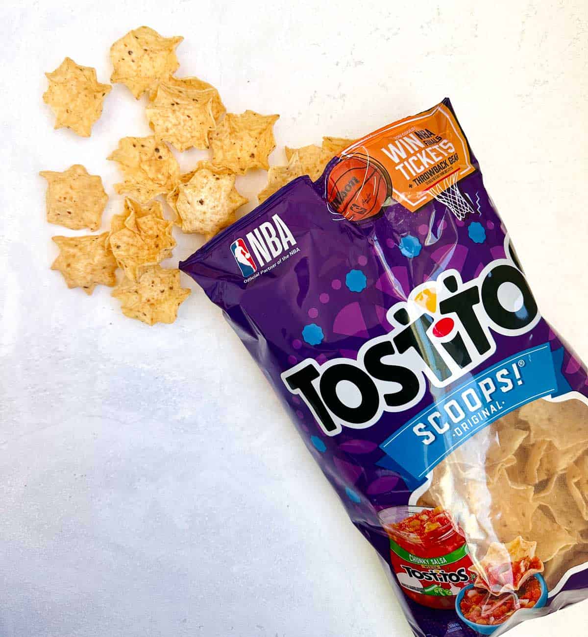 tostitos chip bag open with chips coming out on white background