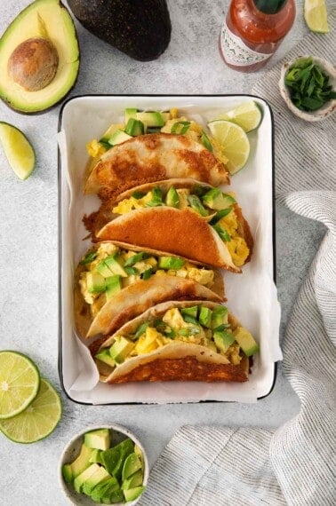 an overhead view of breakfast tacos in a baking dish with parchment paper