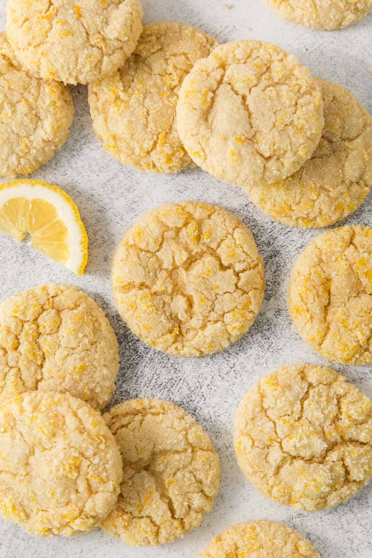 Lemon cookies on parchment paper with a wedge of lemon