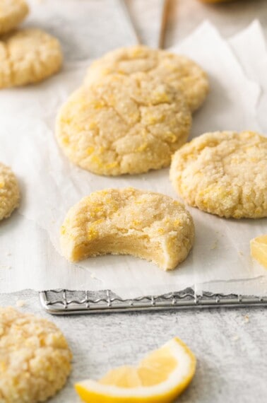 Lemon cookies on a cooling rack with a bite taken out of one