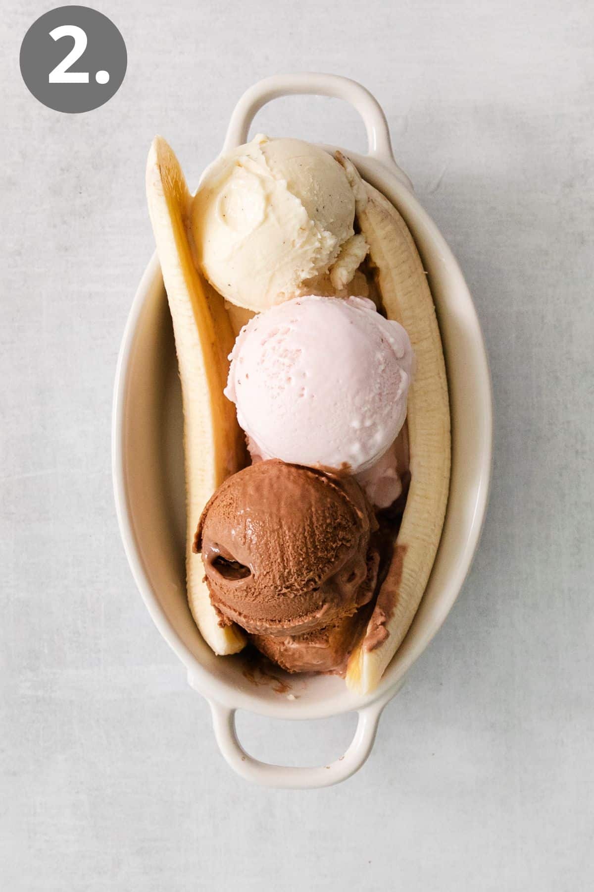 Three ice cream scoops and banana slices in a dish