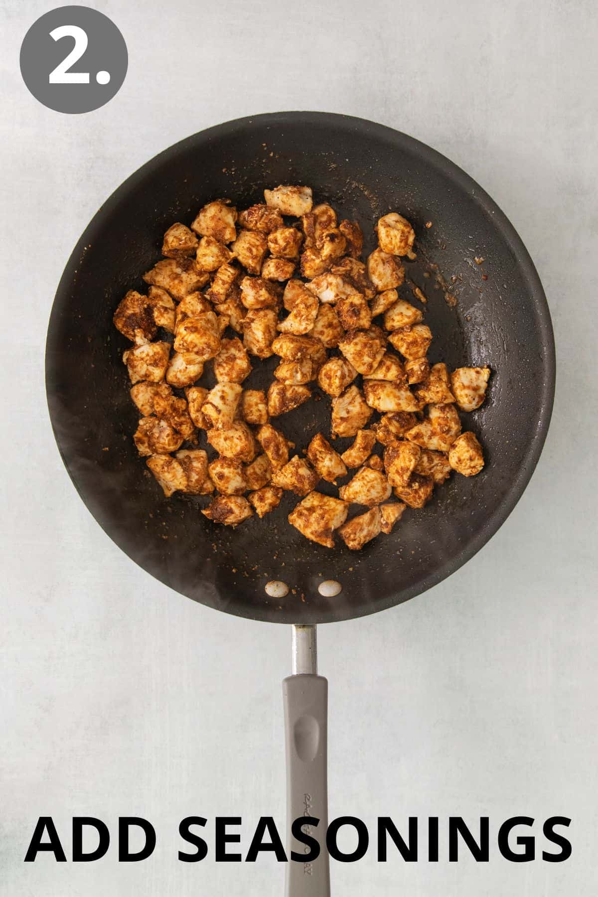 Cooked chicken in a skillet with seasoning added on top