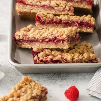 Gluten-free raspberry bars stacked in a baking dish
