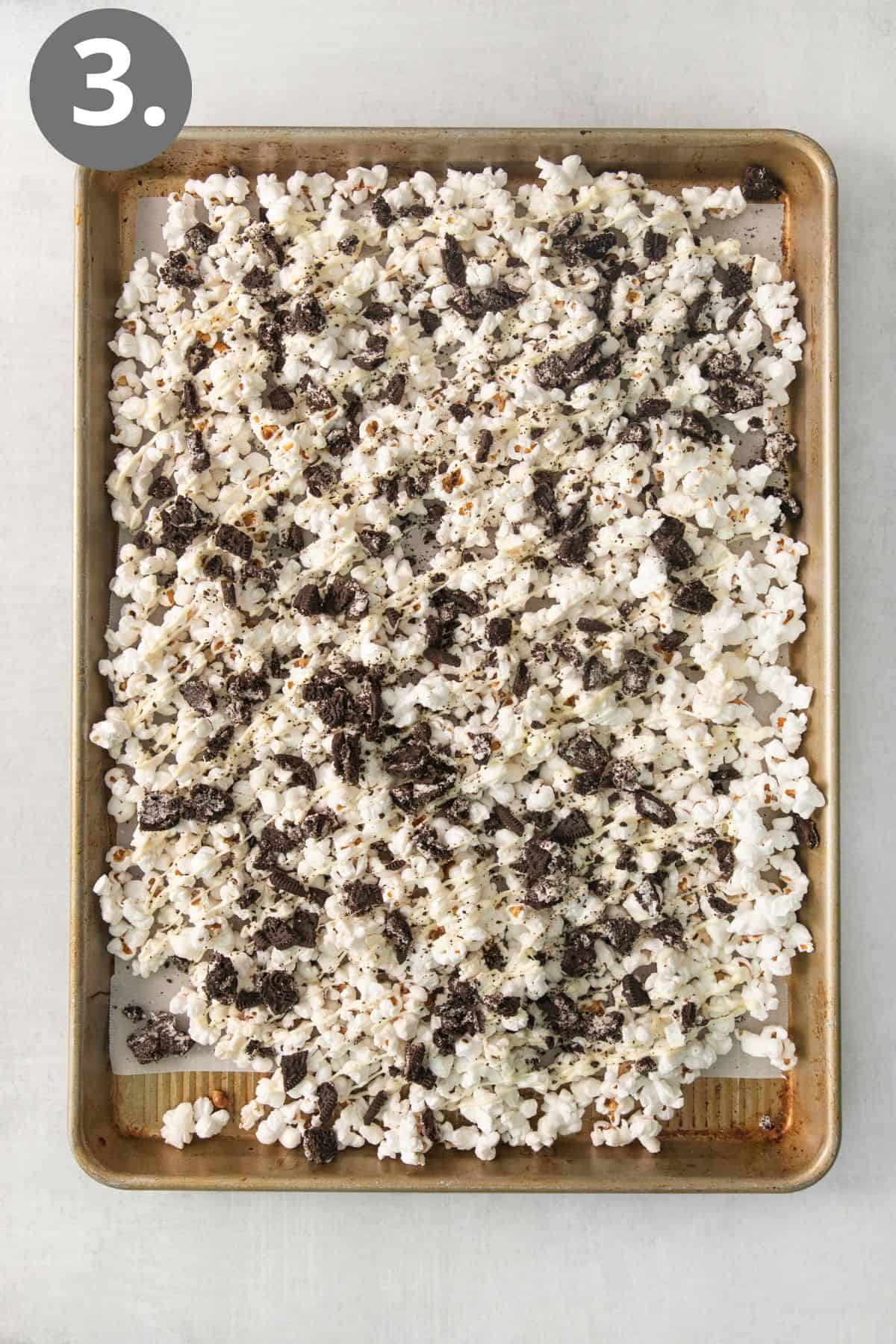 Oreo popcorn spread on a baking tray