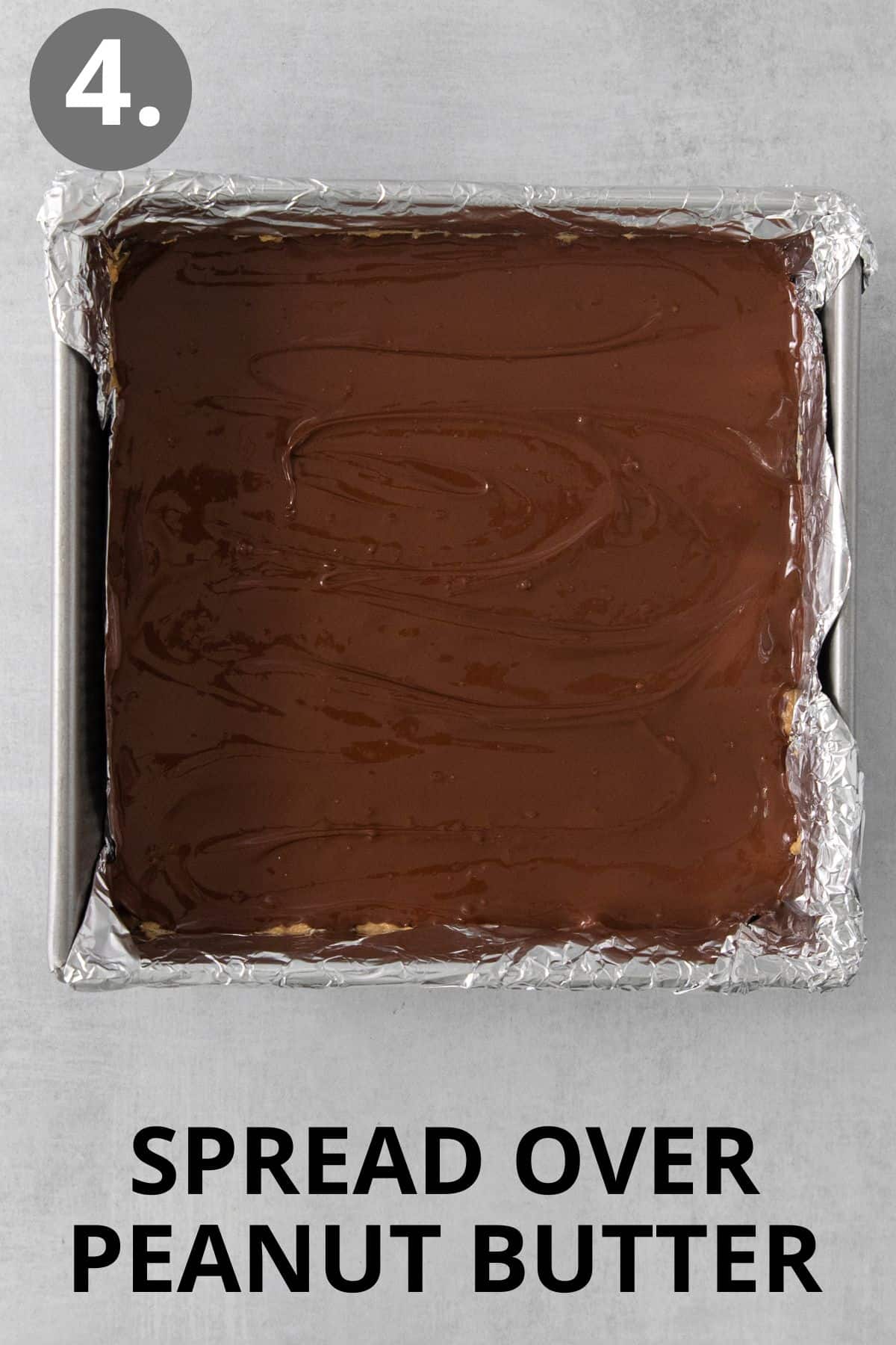 Chocolate spread over peanut butter bars in a pan