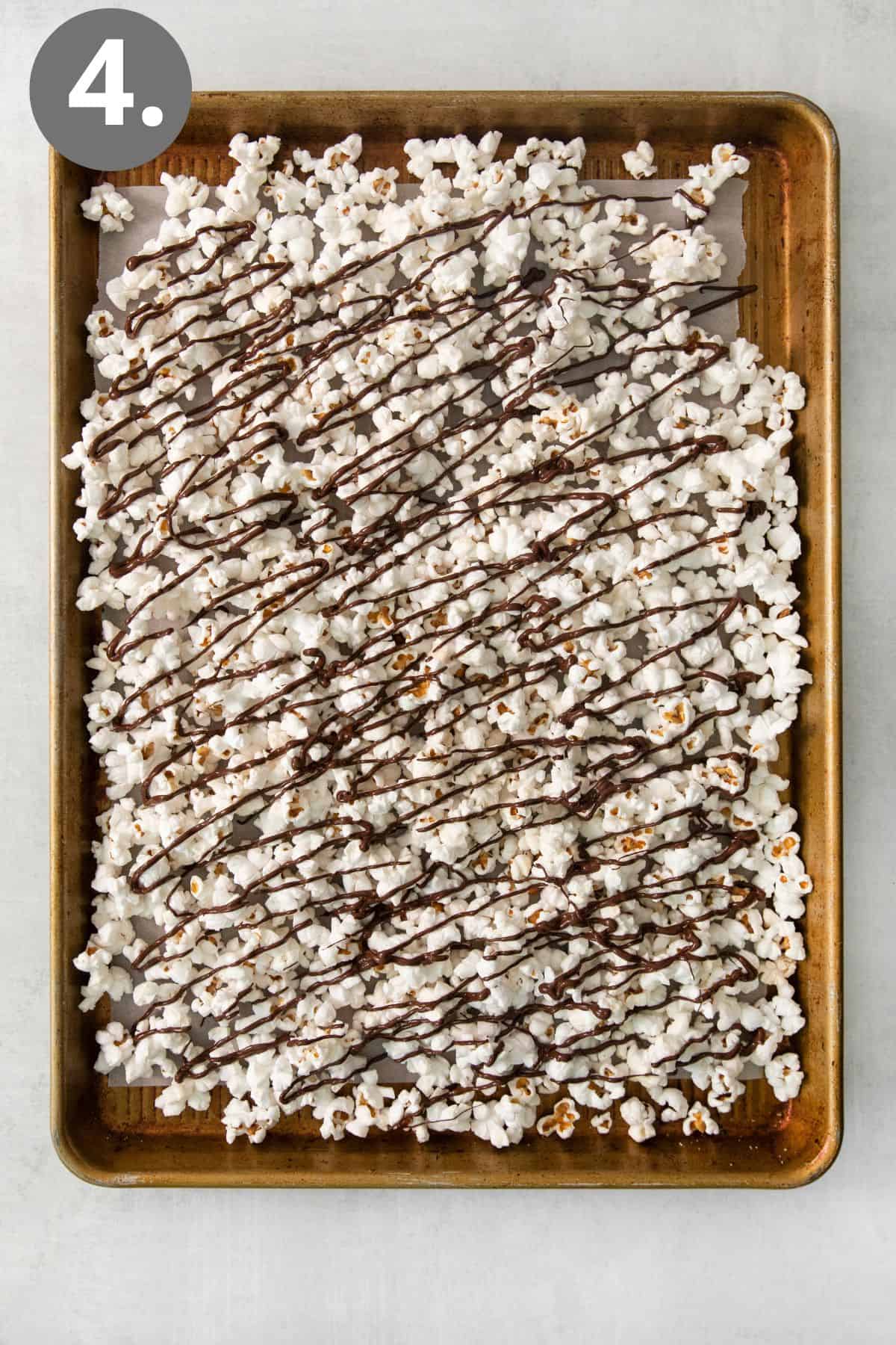 Popcorn drizzled with chocolate on a baking tray