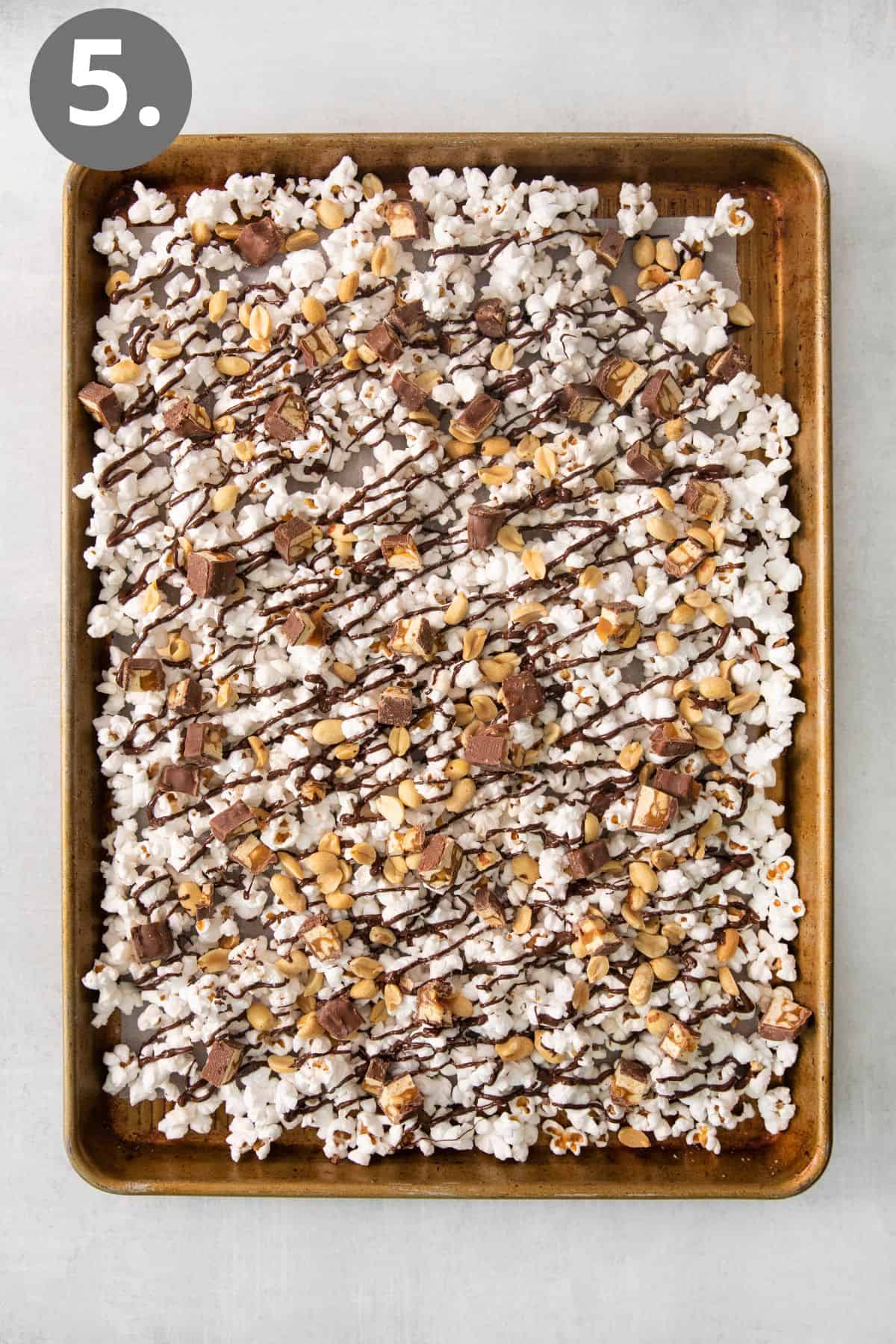 Popcorn drizzled with chocolate, Snickers bars, and peanuts