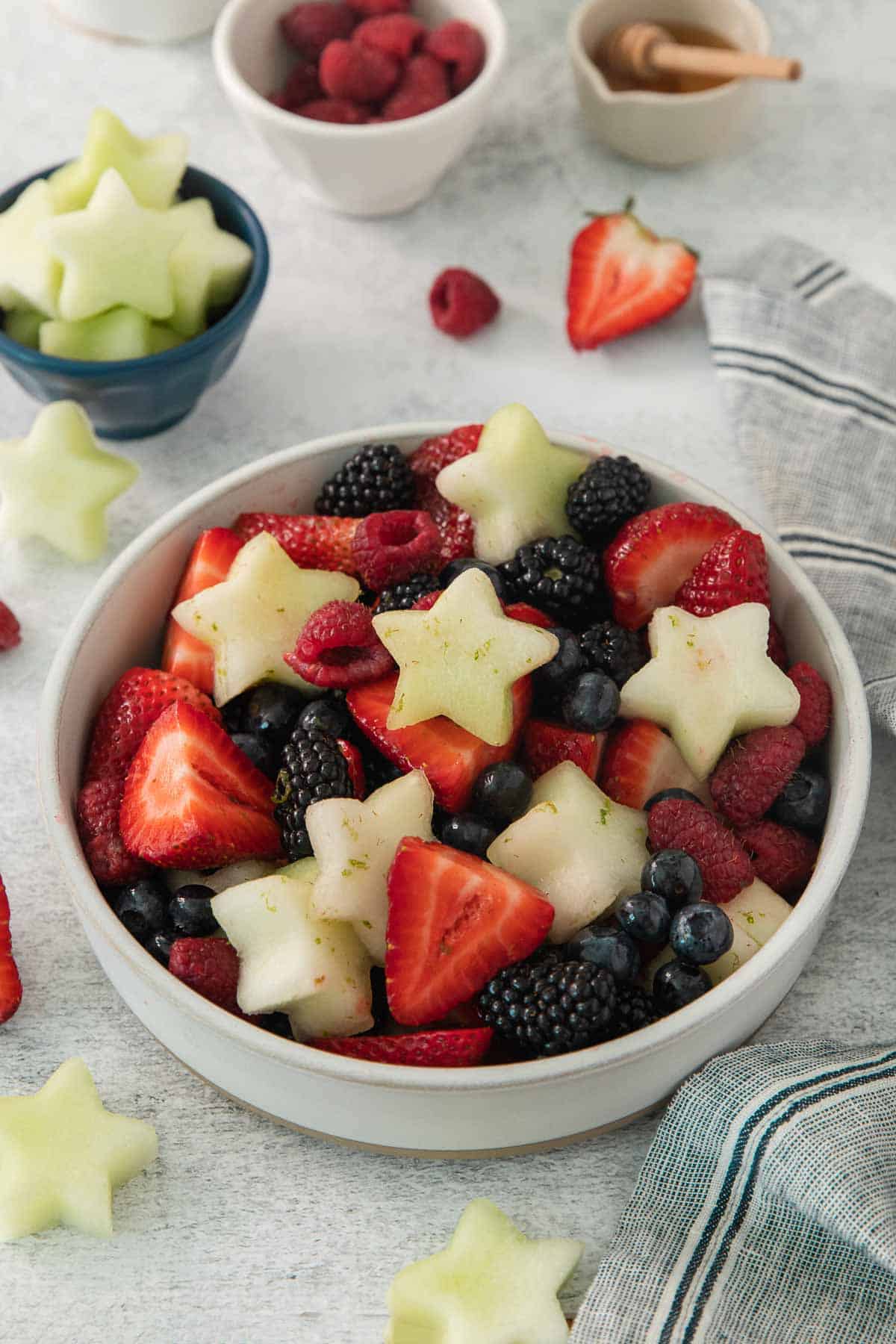 side angle shot of Fourth of July fruit salad in a bowl with fruit surrounding it