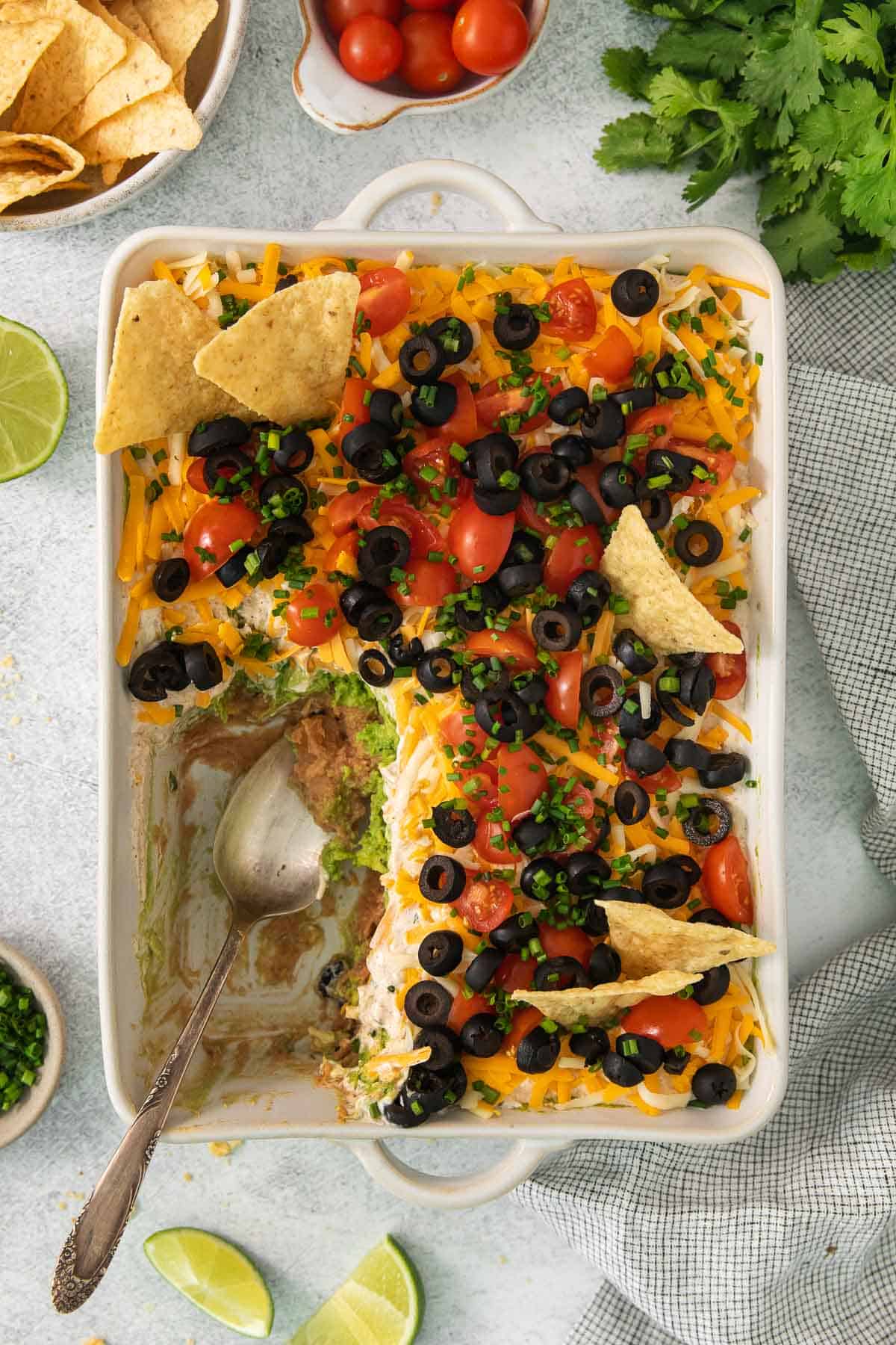 overhead shot of 7-layer taco dip in a baking dish with a portion scooped out
