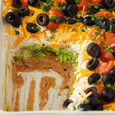 7-layer taco dip in a baking dish with a portion scooped out