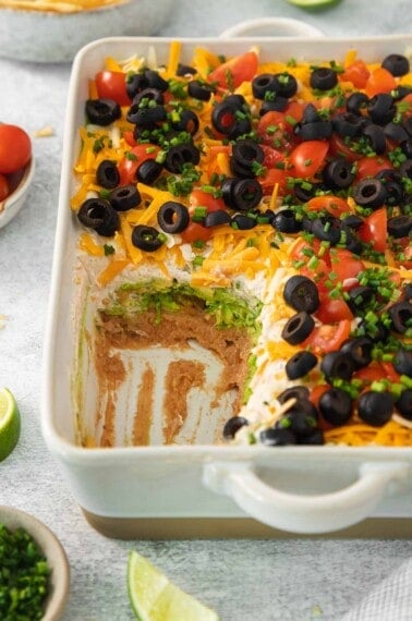 7-layer taco dip in a baking dish with a portion scooped out
