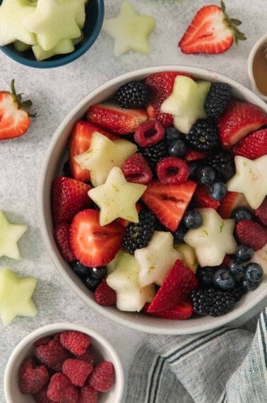 Fourth of July fruit salad in a bowl with fruit surrounding it