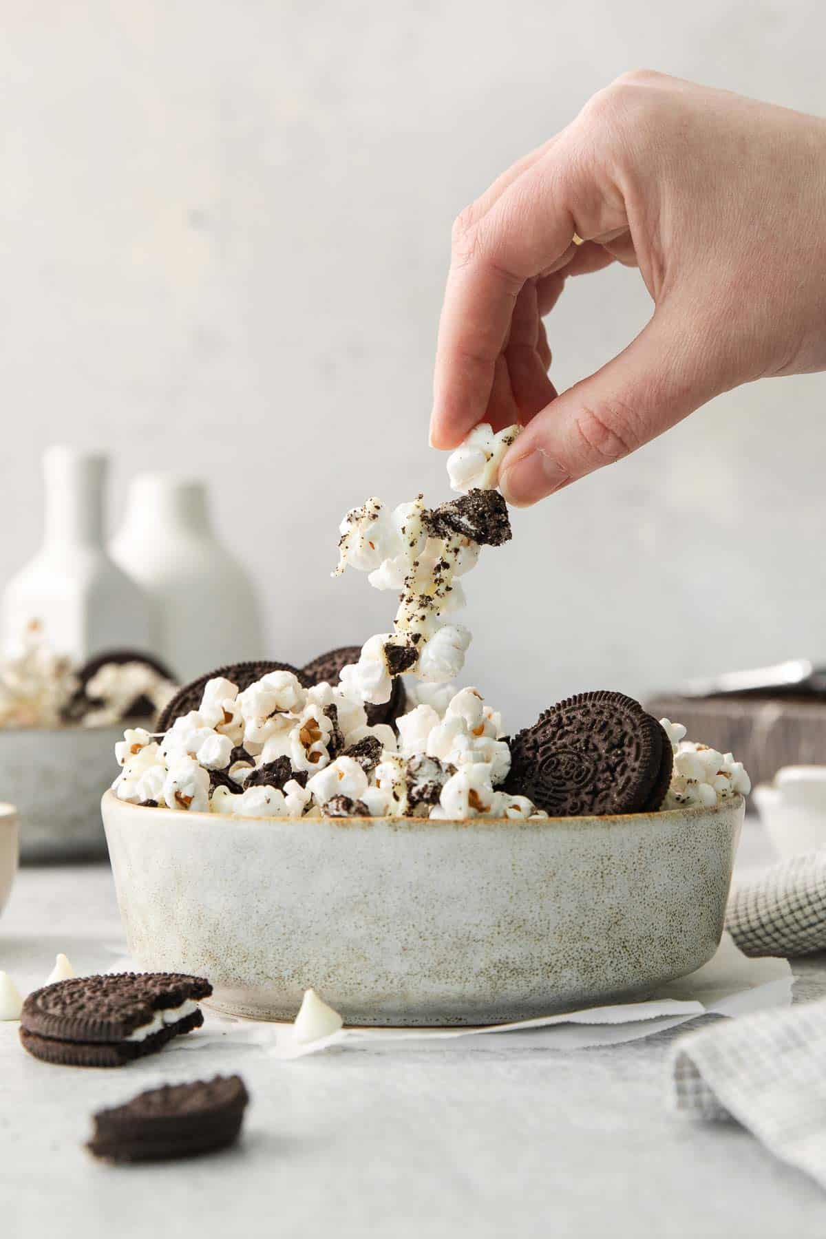 Oreo popcorn in a bowl with a hand picking up a piece