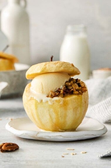 A baked apple with filling and a scoop of ice cream on a plate