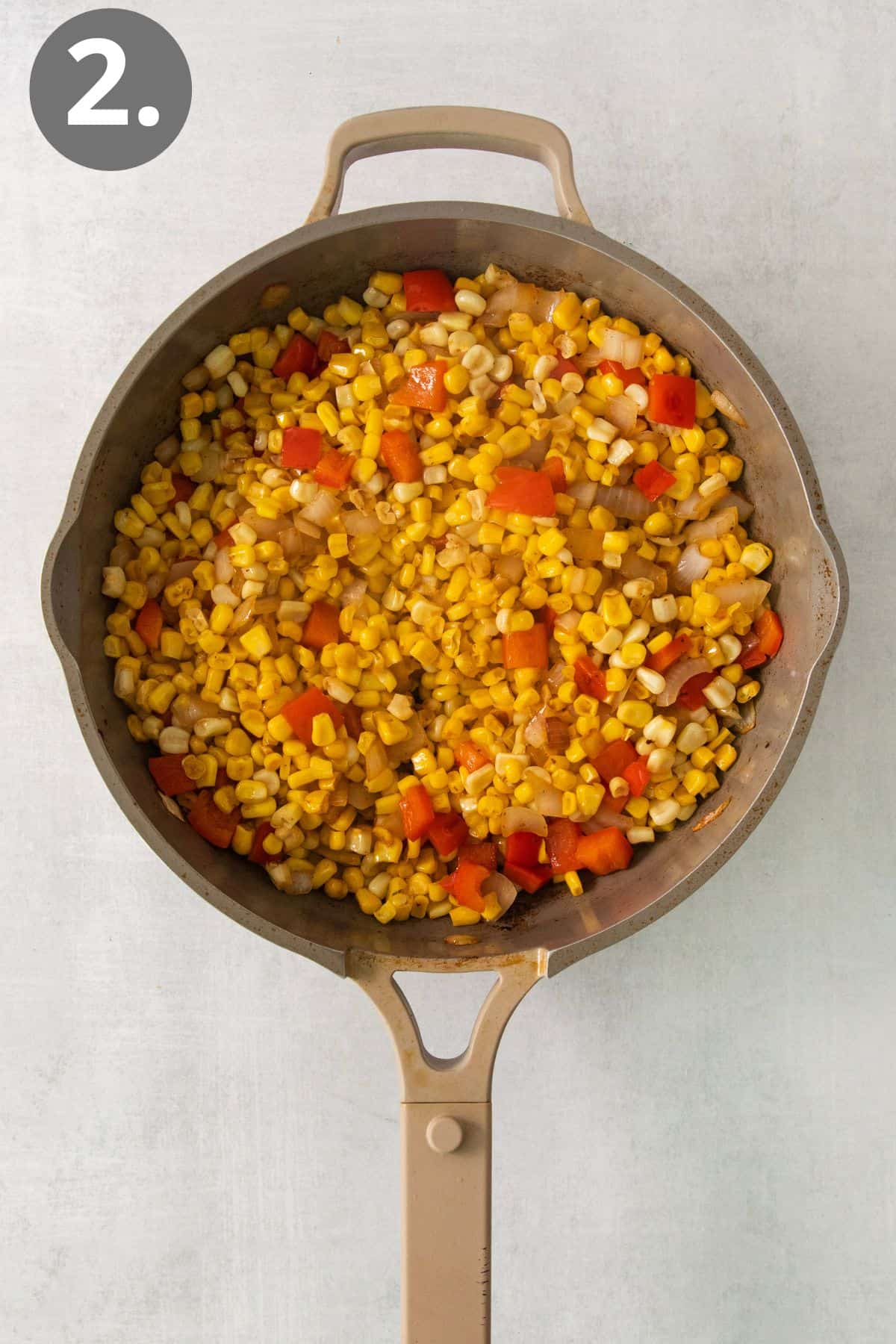 Corn, onion, peppers, and other ingredients cooking in a skillet