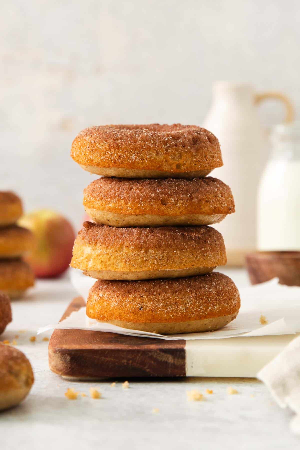 Gluten-free apple cider donuts stacked on a wooden board
