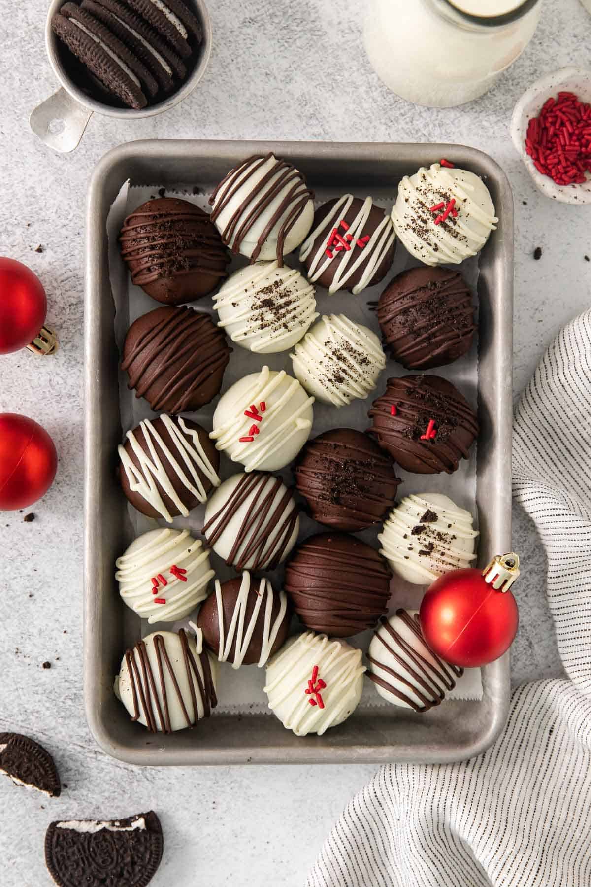 An overhead view of gluten-free Oreo truffles on a baking sheet with ornaments around it