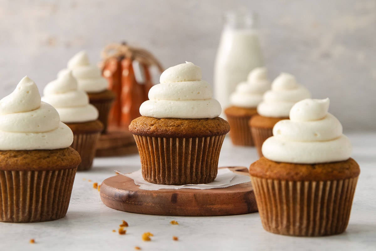 Gluten-free pumpkin cupcakes on a countertop with milk in the background