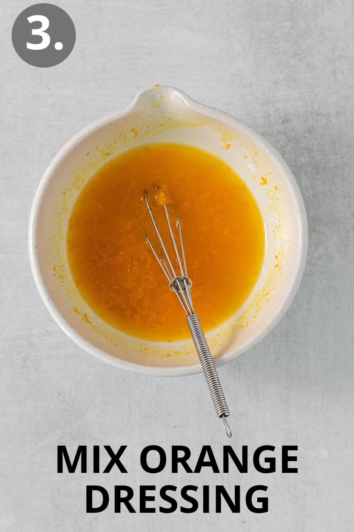 Orange dressing and a whisk in a mixing bowl